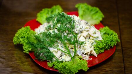 Cooked salad with ingredients: boiled chicken eggs and smoked breast, cheese, pickled cucumber, onion and parsley greens, salad leaves, salt, black pepper, mayonnaise.の写真素材