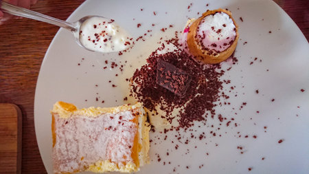 On the wooden table: custard cake, ice cream in a waffle cone, ice cream sprinkled with chocolate...