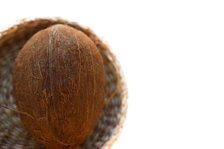 One Coconut In A Wicker Plate In Selective Focus. Isolated Image On A White Background With Copy...