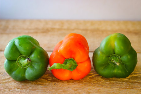Red and green bell peppers on a wooden boardの写真素材