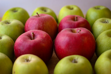 Green and red apples stand on a wooden surfaceの写真素材