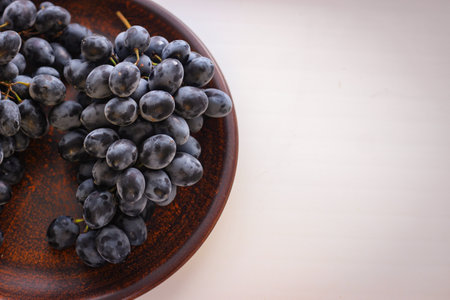 Blue grapes on a clay plate with copy spaceの写真素材