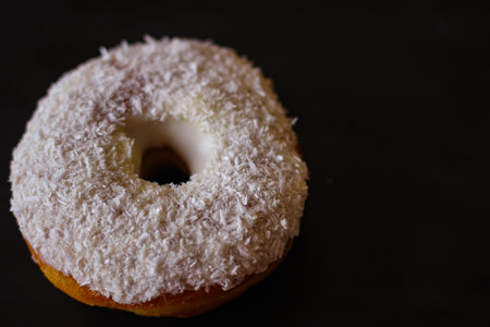 Delicious Donuts with coconut shavings on a black backgroundの写真素材