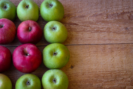 Green and red apples stand on a wooden surfaceの写真素材