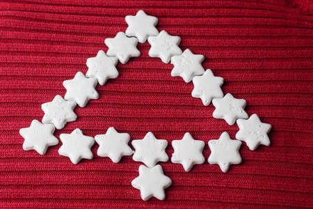 Hexagonal star-shaped cookies are on display in the shape of a Christmas tree standing on a red clothの写真素材