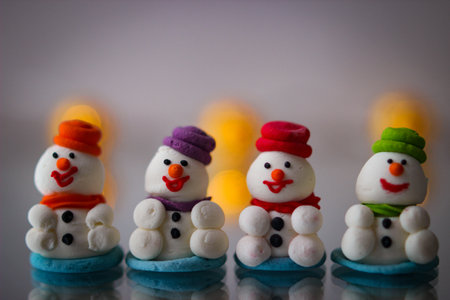 Christmas decor. A miniature figures of powdered sugar snowman with a colorful hat stands on a mirror.の写真素材