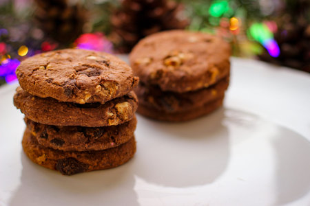 Christmas motifs. Delicious cookies for Santa stands on white plate. In background of spruce branch