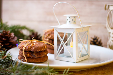 Christmas motifs. Delicious cookies for Santa stands on white plate. In background of spruce branch