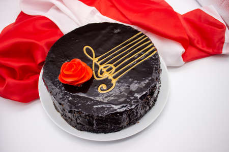 Round chocolate cake with red rose and music staff on white backgroundの写真素材