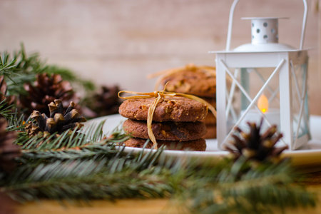 Christmas motifs. Delicious cookies for Santa stands on white plate. In background of spruce branch