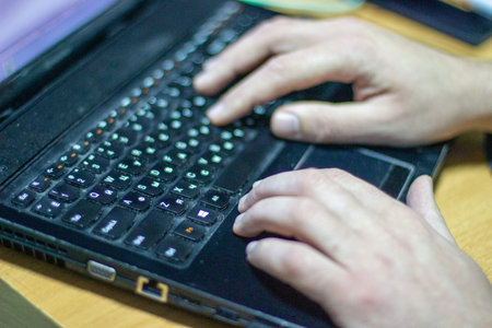 Man works on laptop with cyclic keyboard. blurry photo