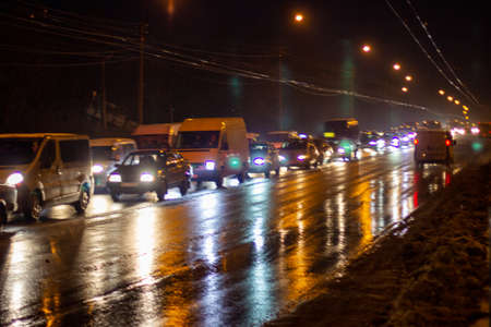 Evening photo. Cars drive on road in evening city with headlights onの写真素材