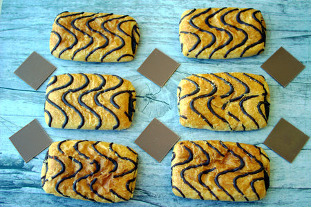 Wonderful biscuit cakes poured with chocolate stand on wooden background