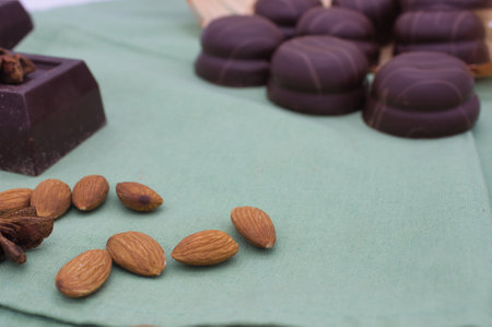 Chocolate candies with almonds and spices on a green napkinの写真素材