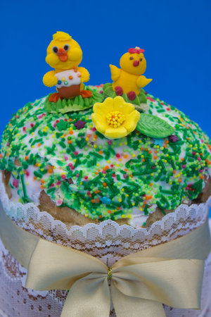 Close-up of an Easter cake with icing, colorful sprinkles, and sugar figures of chicks, decorated...
