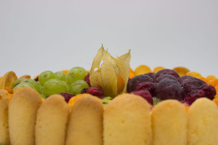 This close-up of a vibrant fruit tart highlights an array of juicy berries, grapes, kiwi, and...