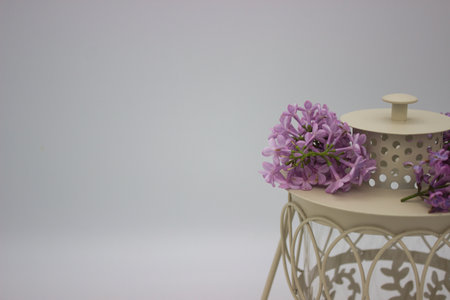 A charming beige lantern adorned with a crown of fresh lilac flowers. The delicate lilacs add a natural, floral touch to the vintage design, evoking springtime and elegance.の写真素材