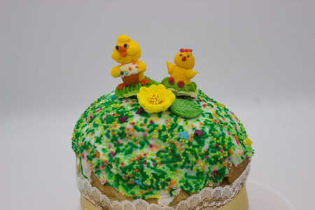 A traditional Easter cake decorated with white icing, colorful sprinkles, sugar figures of chicks,...