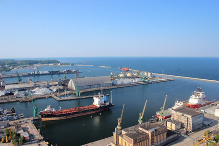 Aerial view of seaport with cargo ships, cranes, and storage facilities on a sunny summer day by the Baltic Sea coast.の写真素材