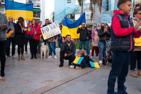 Estepona, Andalusia, Spain -  March. 05, 2022. Protestors rally in support of Ukraine against russian agression. Anti-war demonstration. Father with kids is holding picket banner 'No war!"のeditorial素材