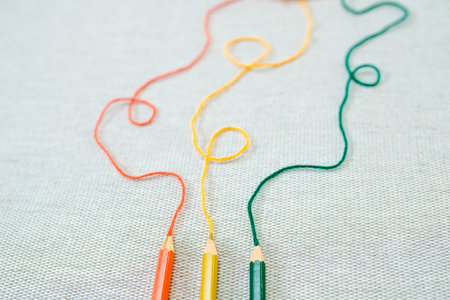 Closeup of three colored pencils thith threads of same color that go up and get blurred. Concept of...