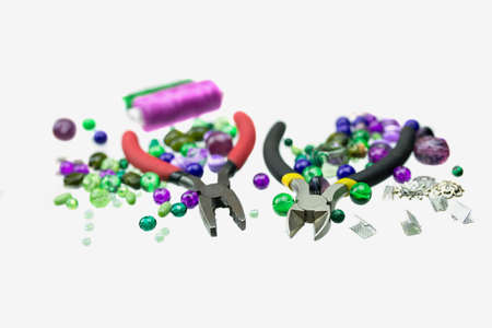 A handfull of green and violet beads, sewing threads and other jewellery suppliers isolated on a white background. Selective focus. Close up.の写真素材