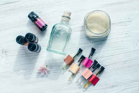 Cosmetic jars, flasks and testers with herbal creams and essenses layed on a white wooden board with...