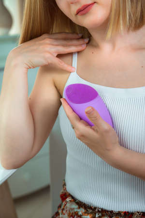 Closeup of violet device with area of pimples in a hand of young woman. Silicone massager and skin cleanser.の写真素材