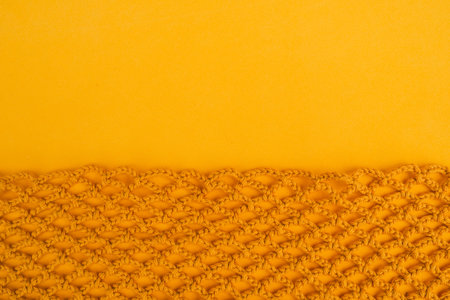 Yellow crochet net background with smooth empty space above. Crochet texture.