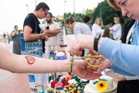 Malaga, Andalusia, Spain -  October 22, 2022. A woman is wrapping a bracelet around the wrist of another lady at charity market.のeditorial素材