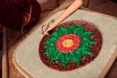 Closeup of textured embroidery sample made of woolen yarn in a hoop with blurred punch needle...