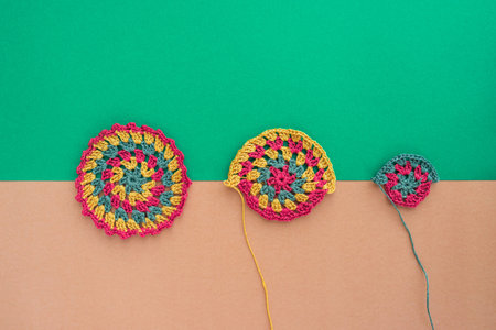 Crochet round motif and two same unfinished motifs laid in horizontal line on the edge of two ...