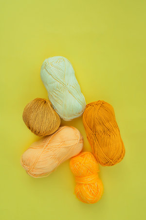 Five skeins of different yarns in yellow tones on yellow background. Materials for fiber art and...
