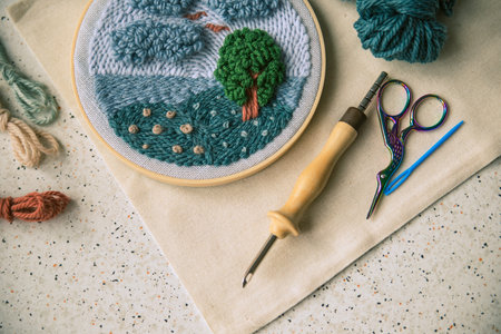 Part view of framed embroidery with focus on instruments that serve for making it and some woolen...