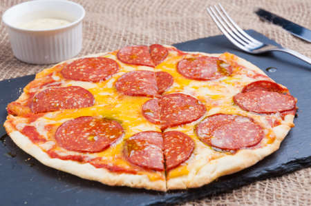 small tasty pepperoni pizza with sauce and olive oilの写真素材