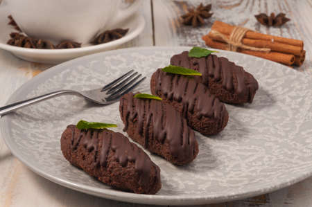 luxury handmade chocolate bars on a light plate with a Cup and cinnamon sticksの写真素材