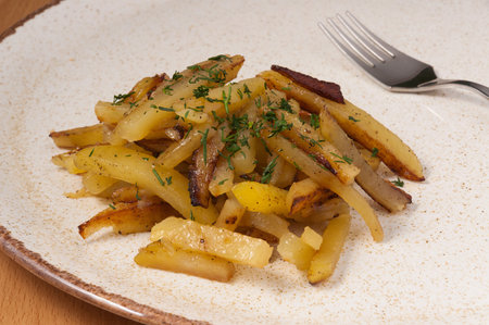 tasty home-made fried potatoes with greens. close up