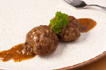 two tasty beef meatballs on a plate of greens. close up