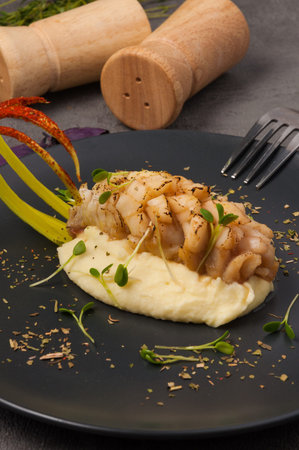 tasty white fish with mashed potatoes on a black plate