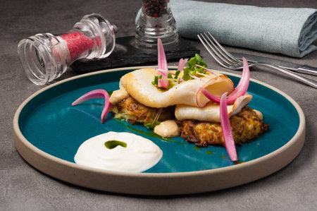 tasty grilled squid with potato pancakes with onions and sour cream