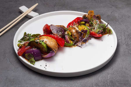 tasty baked vegetables and mushrooms on a white plateの写真素材