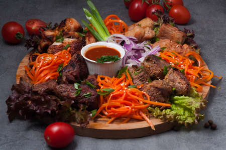 tasty assorted shish kebabs with carrots and tomato sauce on a wooden boardの写真素材
