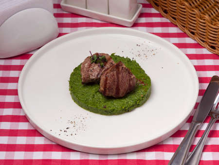 tasty veal medallions on a pillow of spinach and dried tomatoesの写真素材