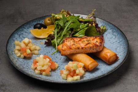 tasty grilled salmon with french fries, salad, side dish of salmon with cucumberの写真素材