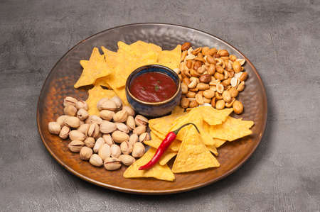 tasty beer snacks: nachos with salsa sauce, pistachios, peanutsの写真素材