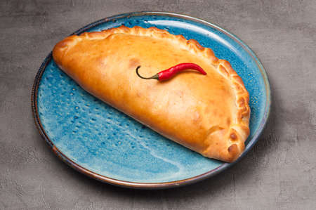 tasty traditional Italian pizza calzone decorated with chili pepperの写真素材