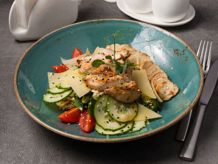 tasty caesar salad in a blue plate on a gray background in a restaurantの写真素材