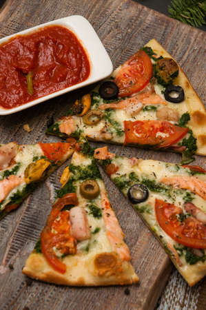 salmon and broccoli tasty pizza with tomato sauce on a wooden boardの写真素材
