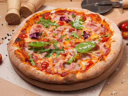 tasty bacon pizza with tomato sauce garnished with spinach and arugulaの写真素材