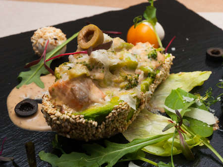 tasty salmon in cream sauce baked in half an avocadoの写真素材